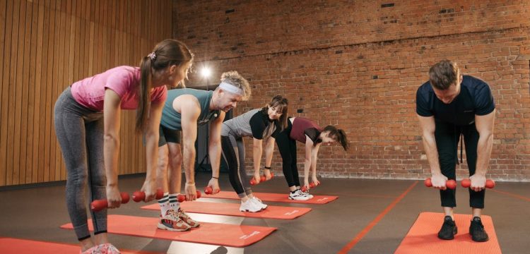 Fitness group performing exercises with dumbbells in a modern yoga studio setting.