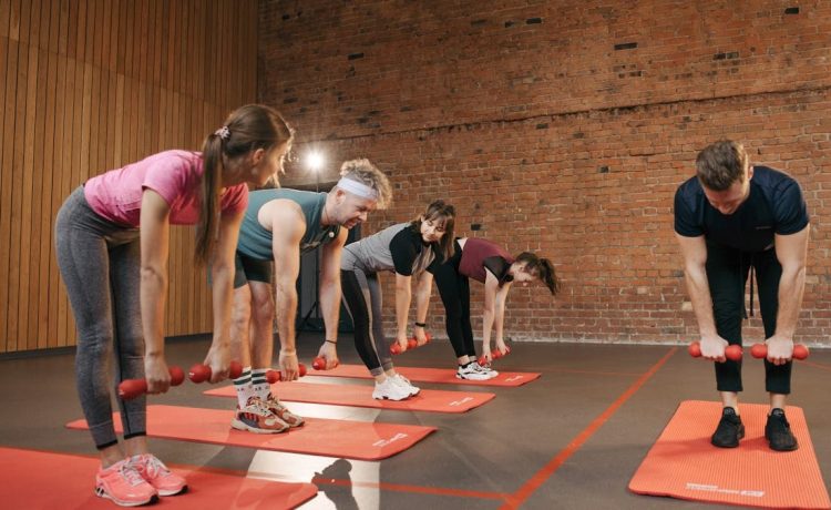 Fitness group performing exercises with dumbbells in a modern yoga studio setting.